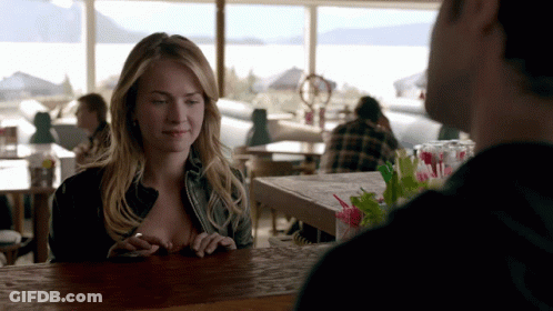 Woman Sitting At Bar Looking At Phone GIF