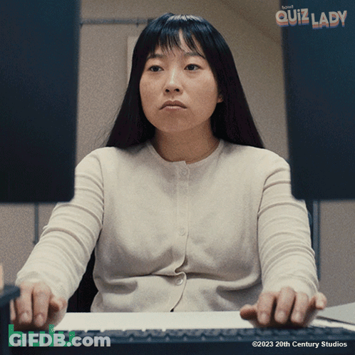 A Woman Sits At A Desk In Front Of A Computer Screen With The Words Quiz Lady Written Above Her GIF