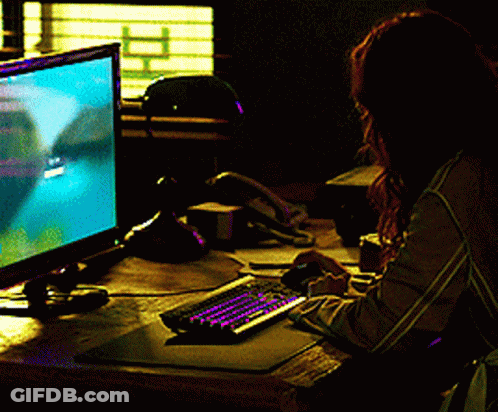 A Woman Sits At A Desk Playing A Video Game On A Computer GIF