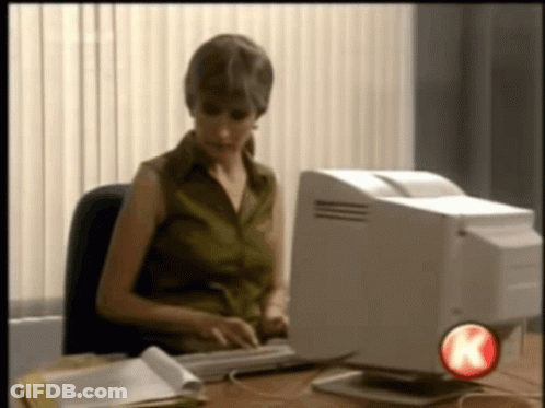 A Woman Sits At A Desk Typing On A Keyboard In Front Of A Computer With A Red K On The Bottom Right GIF