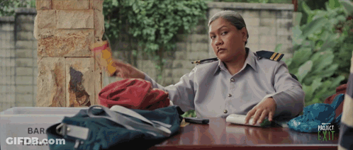 A Woman Sits At A Desk With A Sign That Says Bar Terla GIF