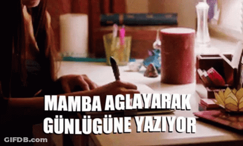 A Woman Sits At A Desk Writing In A Notebook And The Words Mamba Aglayarak Gunlugune Yaziyor Are Above Her GIF
