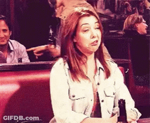 A Woman Sits At A Table With A Bottle Of Beer In Her Hand GIF