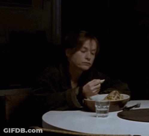 A Woman Sits At A Table With A Bowl Of Food And A Glass Of Water In Front Of Her GIF