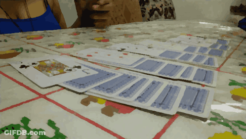 A Woman Sits At A Table With A Bunch Of Playing Cards GIF