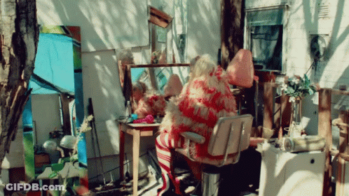 A Woman Sits In A Chair In Front Of A Mirror GIF