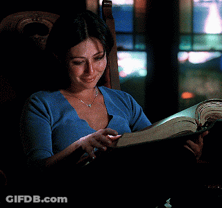 A Woman Sits In A Chair Reading A Book GIF