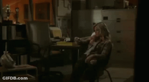 A Woman Sits In A Chair Talking On A Phone GIF