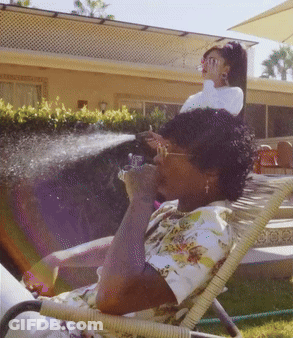 A Woman Sits In A Chair With A Hose Spraying Her Face GIF