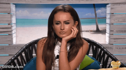 A Woman Sits In A Chair With Her Hand On Her Face GIF