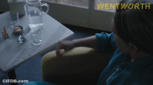 A Woman Sits In A Chair With The Word Wentworth On The Bottom Right GIF