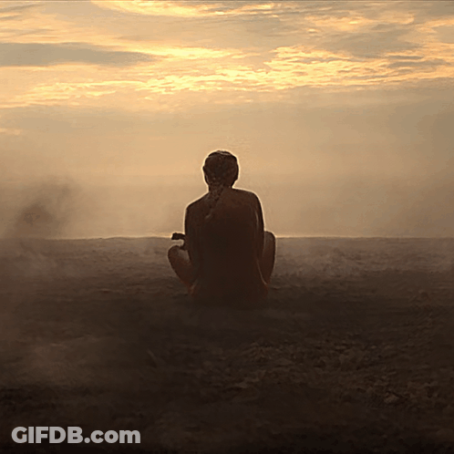 A Woman Sits In A Lotus Position In Front Of A Sunset Sky GIF