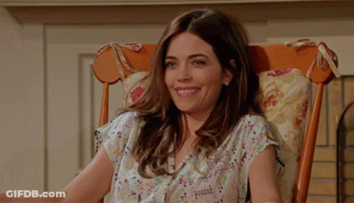 A Woman Sits In A Rocking Chair Smiling GIF