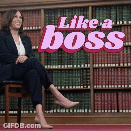 A Woman Sits In Front Of A Bookshelf With The Words Like A Boss Behind Her GIF