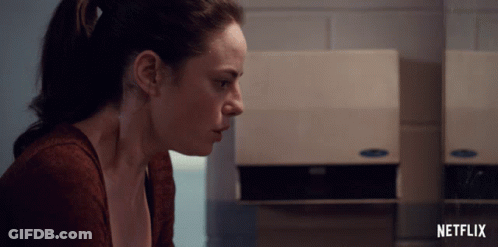 A Woman Sits In Front Of A Netflix Advertisement GIF