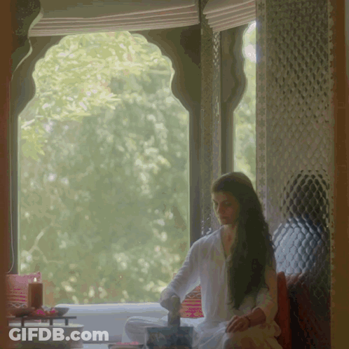 A Woman Sits In Front Of A Window With A Candle GIF