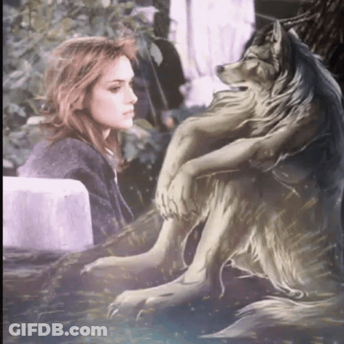 A Woman Sits Next To A Statue Of A Wolf With A Long Mane GIF
