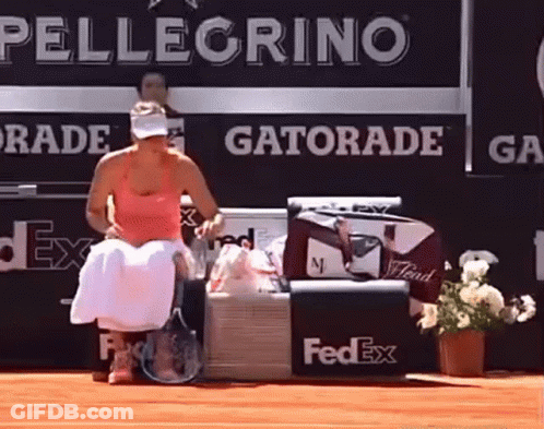 A Woman Sits On A Bench In Front Of A Gatorade Advertisement GIF
