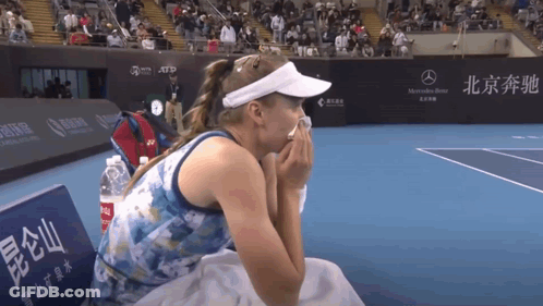 A Woman Sits On A Bench On A Tennis Court With A Mercedes Benz Sign Behind Her GIF