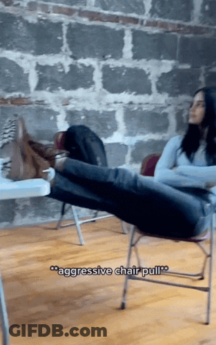 A Woman Sits On A Chair With Her Feet Up And The Words " Aggressive Chair Pull " Above Her GIF