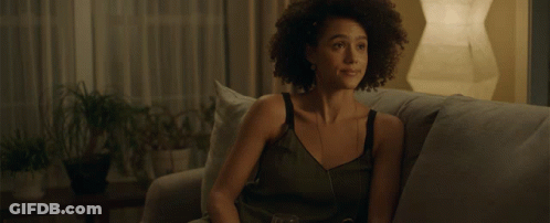 A Woman Sits On A Couch With A Glass Of Wine In Her Hand GIF