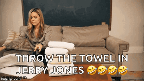 A Woman Sits On A Couch With A Stack Of Towels And The Words Throw The Towel In Jerry Jones Below Her GIF