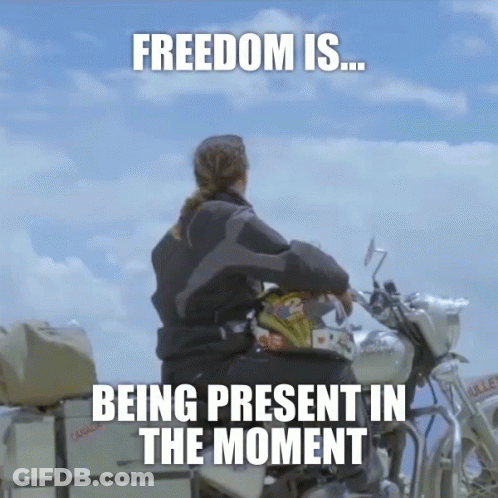 A Woman Sits On A Motorcycle With The Words " Freedom Is Being Present In The Moment " GIF