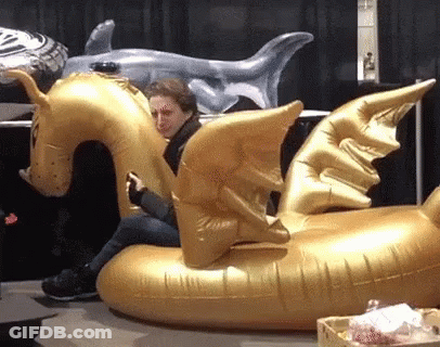 A Woman Sits On An Inflatable Dragon Float GIF
