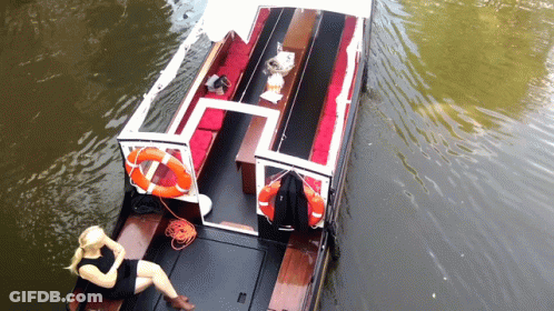 A Woman Sits On The Deck Of A Boat With A Life Preserver Attached To It GIF