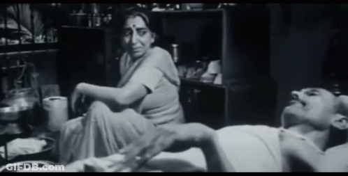 A Woman Sits On The Floor Next To A Man Laying On The Floor GIF