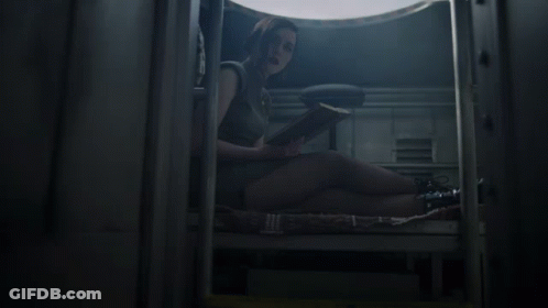 A Woman Sits On The Floor Reading A Book In A Dark Room GIF