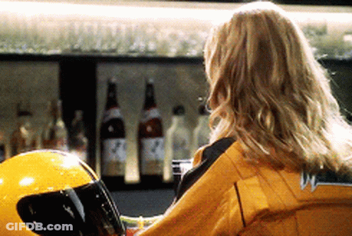 A Woman Sitting At A Bar With A Yellow Helmet GIF