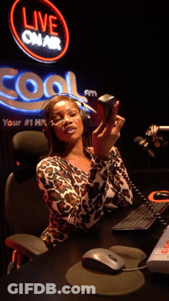 A Woman Sitting At A Desk In Front Of A Sign That Says Live On Air GIF