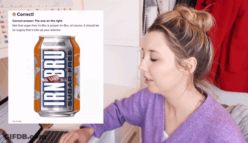 A Woman Sitting At A Desk With A Can Of Iron Bru In Front Of Her GIF