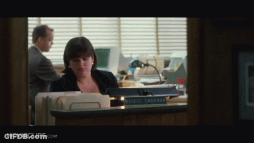 A Woman Sitting At A Desk With A Name Plate That Says Harriet Sherman GIF