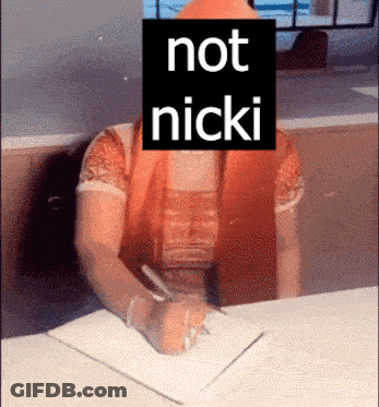 A Woman Sitting At A Desk With A Sign That Says Not Nicki On Her Face GIF