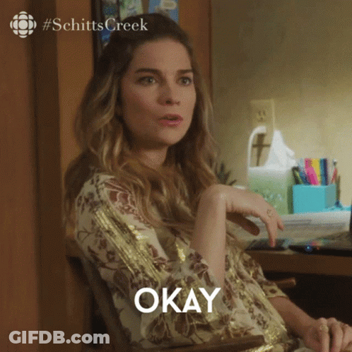 A Woman Sitting At A Desk With The Word Okay Written On The Screen GIF