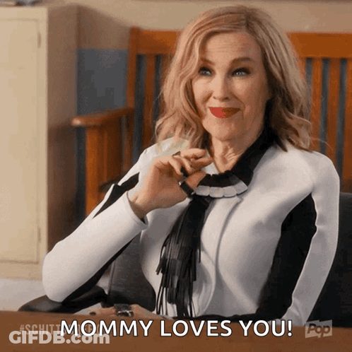 A Woman Sitting At A Desk With The Words " Mommy Loves You " Above Her GIF