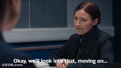 A Woman Sitting At A Desk With The Words " Okay We 'Ll Look Into That Moving On " GIF