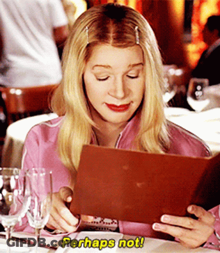 A Woman Sitting At A Table Looking At A Menu With Perhaps Not Written On It GIF