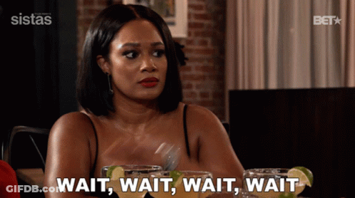 A Woman Sitting At A Table Says Wait Wait Wait Wait While Holding A Fork GIF
