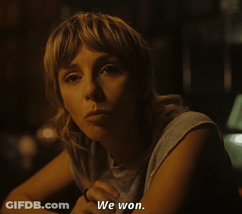 A Woman Sitting At A Table Says " We Won " In A Dark Room GIF