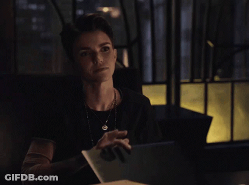 A Woman Sitting At A Table With A Blue Folder In Front Of Her GIF