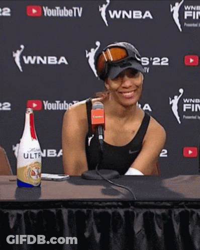 A Woman Sitting At A Table With A Bottle Of Ultra Sitting In Front Of Her GIF
