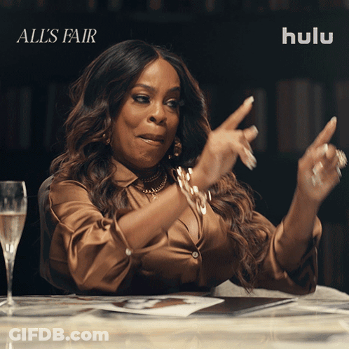 A Woman Sitting At A Table With A Glass Of Champagne And Hulu Written On The Bottom GIF
