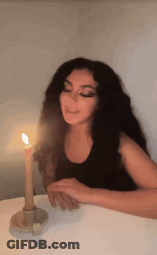 A Woman Sitting At A Table With A Lit Candle GIF