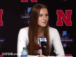 A Woman Sitting At A Table With A Microphone And A Bottle Of Water . GIF