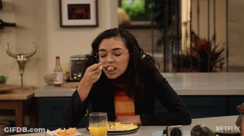 A Woman Sitting At A Table With A Plate Of Food And A Glass Of Orange Juice With Netflix Written On The Bottom GIF