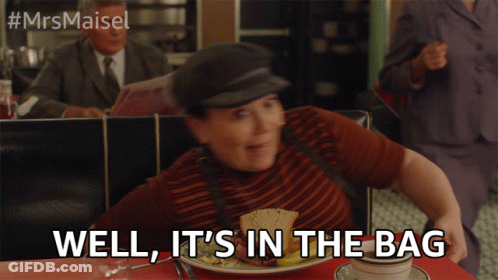 A Woman Sitting At A Table With A Plate Of Food And The Words Well It 'S In The Bag Above Her GIF