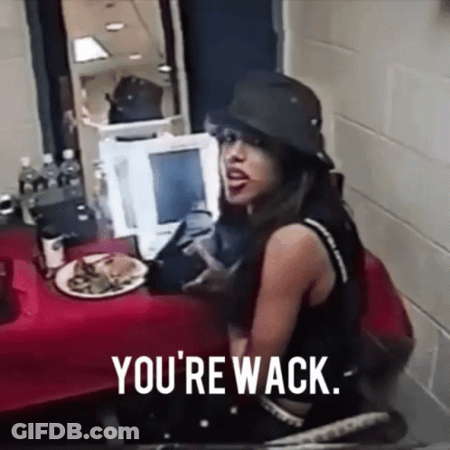 A Woman Sitting At A Table With A Plate Of Food And The Words " You 'Re Wack " GIF